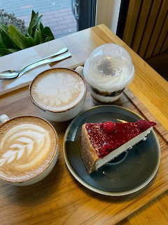 Two lattes and a slice of strawberry cheesecake on a wooden tray