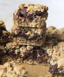 Stack of chocolate oat crumble bars with visible layers of oats and melted chocolate on parchment paper