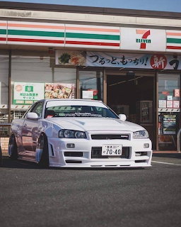 White Nissan Skyline R34 parked in front of a convenience store