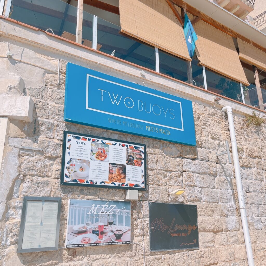 Two Buoys restaurant exterior with blue sign on limestone building in Malta