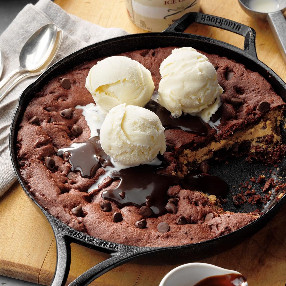 Chocolate chip skillet cookie with vanilla ice cream scoops in cast iron pan