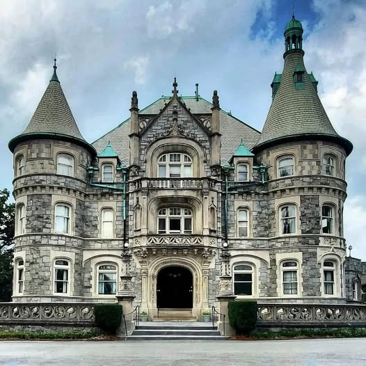 Ornate historic castle with twin towers and elaborate stone facade under cloudy sky
