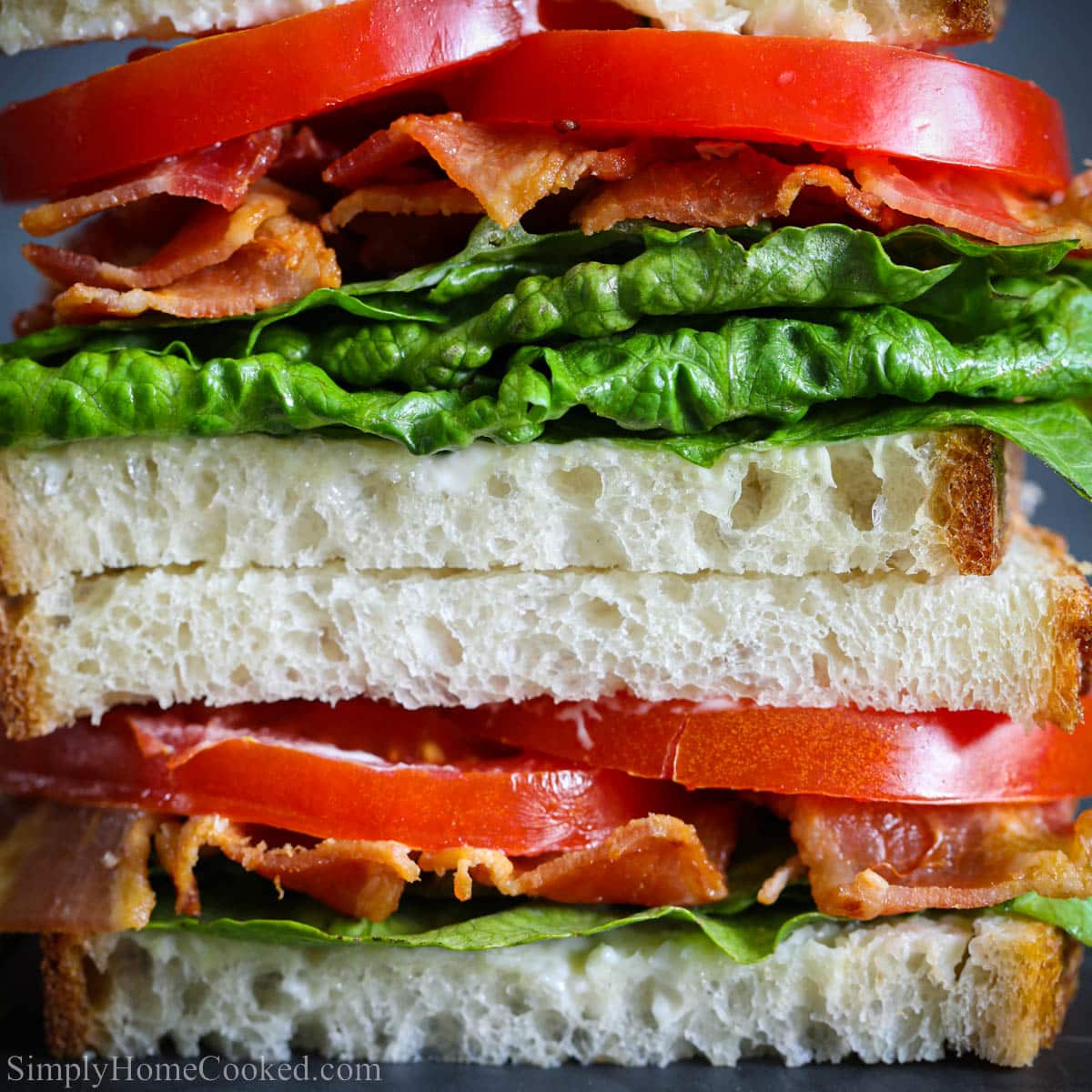 Close-up of a BLT sandwich with bacon, lettuce, tomato, and toasted bread stacked in layers
