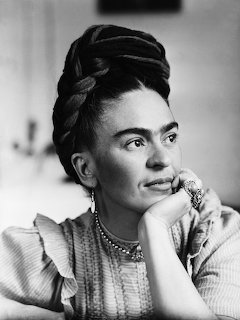 Black and white portrait of Frida Kahlo with braided hair updo, resting chin on hand