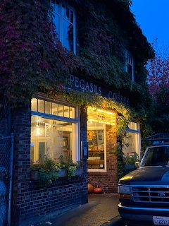 Ivy-covered Pegasus Coffee shop at dusk with warm lights glowing through large windows