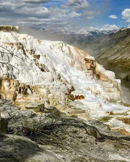White travertine terraces of Mammoth Hot Springs at Yellowstone with mountains in the distance