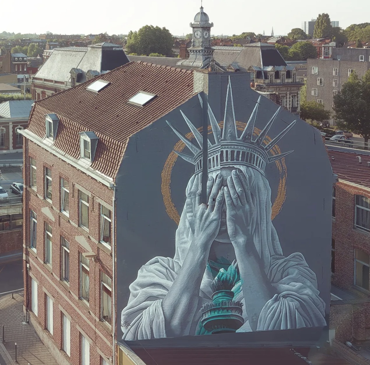 Street art mural of hands covering the Statue of Liberty’s face on the side of a brick building