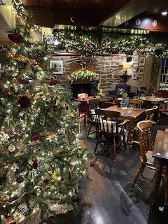 Festive pub interior with decorated Christmas trees, wooden furniture, and warm lighting