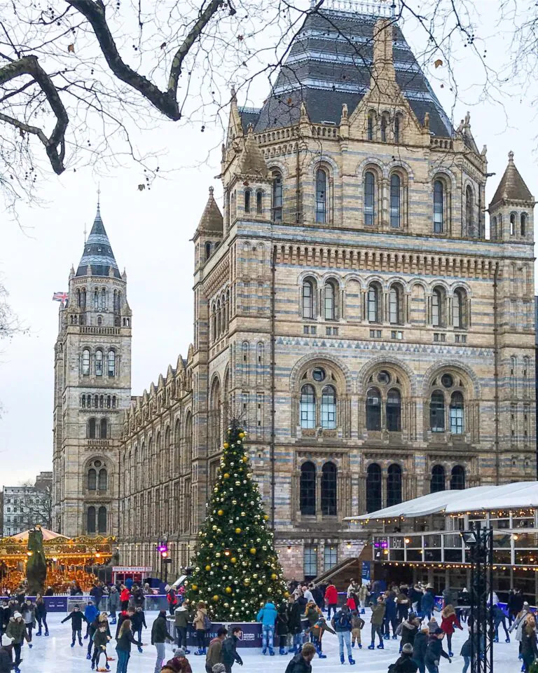 Natural History Museum building in London with winter ice rink and Christmas tree in front courtyard
