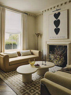 Elegant living room with beige sofas, marble fireplace, and framed black hearts artwork on wall
