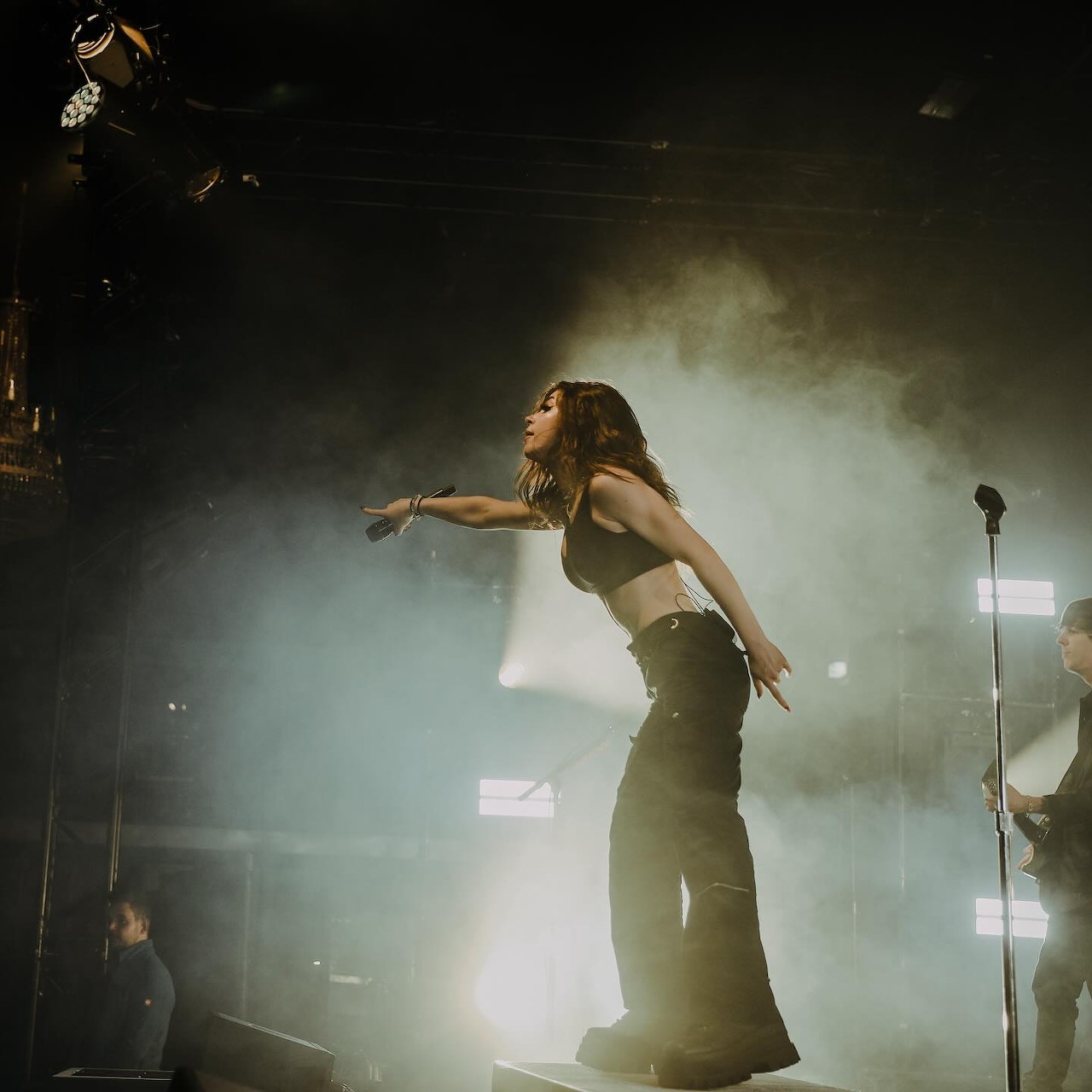 Female singer performing on a smoky stage with bright lights and a microphone stand