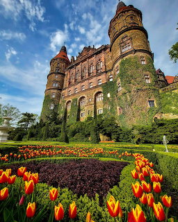 Książ Castle in Poland with vibrant tulip garden in foreground and blue sky above