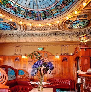 Ornate art nouveau café with stained glass dome, decorative walls, and warm lighting