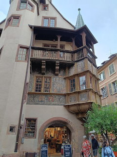 Old building facade with carved wooden balconies and an arched entryway on a street