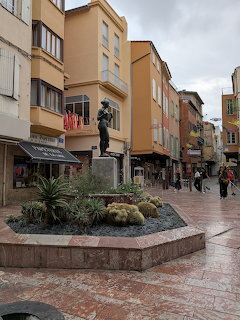 Statue on fountain in pedestrian square surrounded by colorful buildings in Perpignan, France
