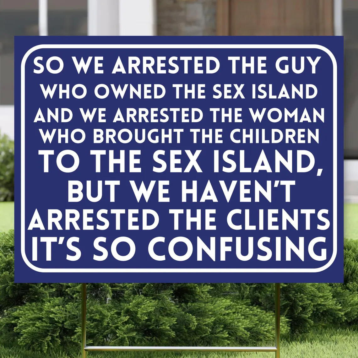 Blue sign with large white text outdoors in front of green bushes