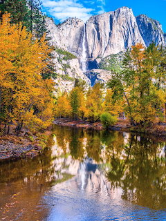 Yosemite Falls with autumn trees reflected in a calm river in Yosemite Valley