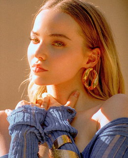 Young woman with blonde hair and large gold hoop earrings gazing to the side in warm sunlight
