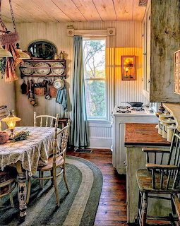 Rustic vintage kitchen with wooden walls, table, chairs, hanging cookware, curtained window and glowing lamp