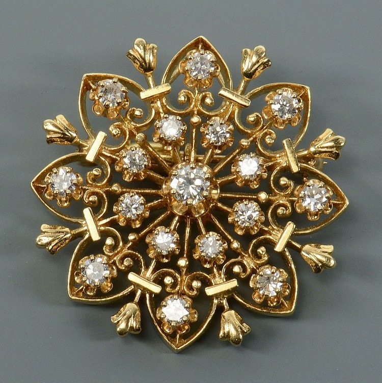 Antique gold brooch with circular floral design and diamonds on a gray background
