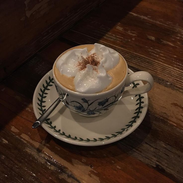 Vienna coffee with foam and cocoa on decorated cup and saucer on wooden table