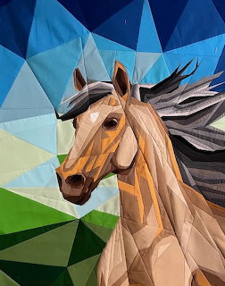 Geometric quilted horse portrait with angular patches in browns and tans against blue and green background