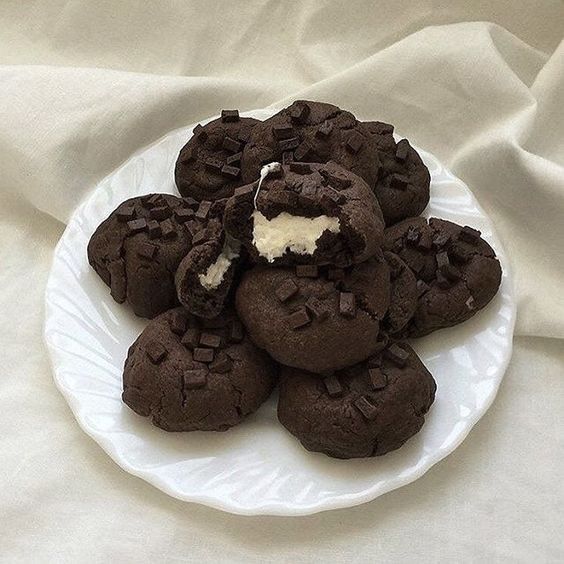 Chocolate cookies with cream filling stacked on white plate