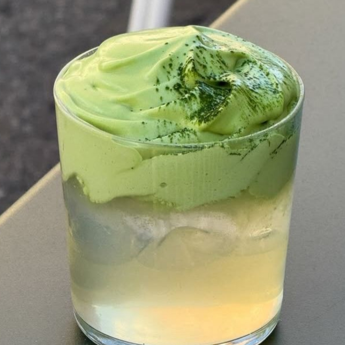 Glass of iced coconut matcha with thick green matcha cream layered over a clear drink