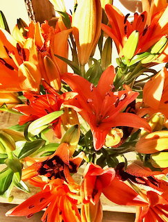 Close-up of a bouquet of bright orange lilies with green buds and leaves