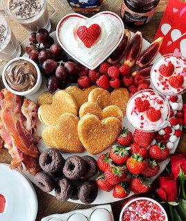 Valentine's Day breakfast board with heart-shaped pancakes, strawberries, chocolates, and romantic treats