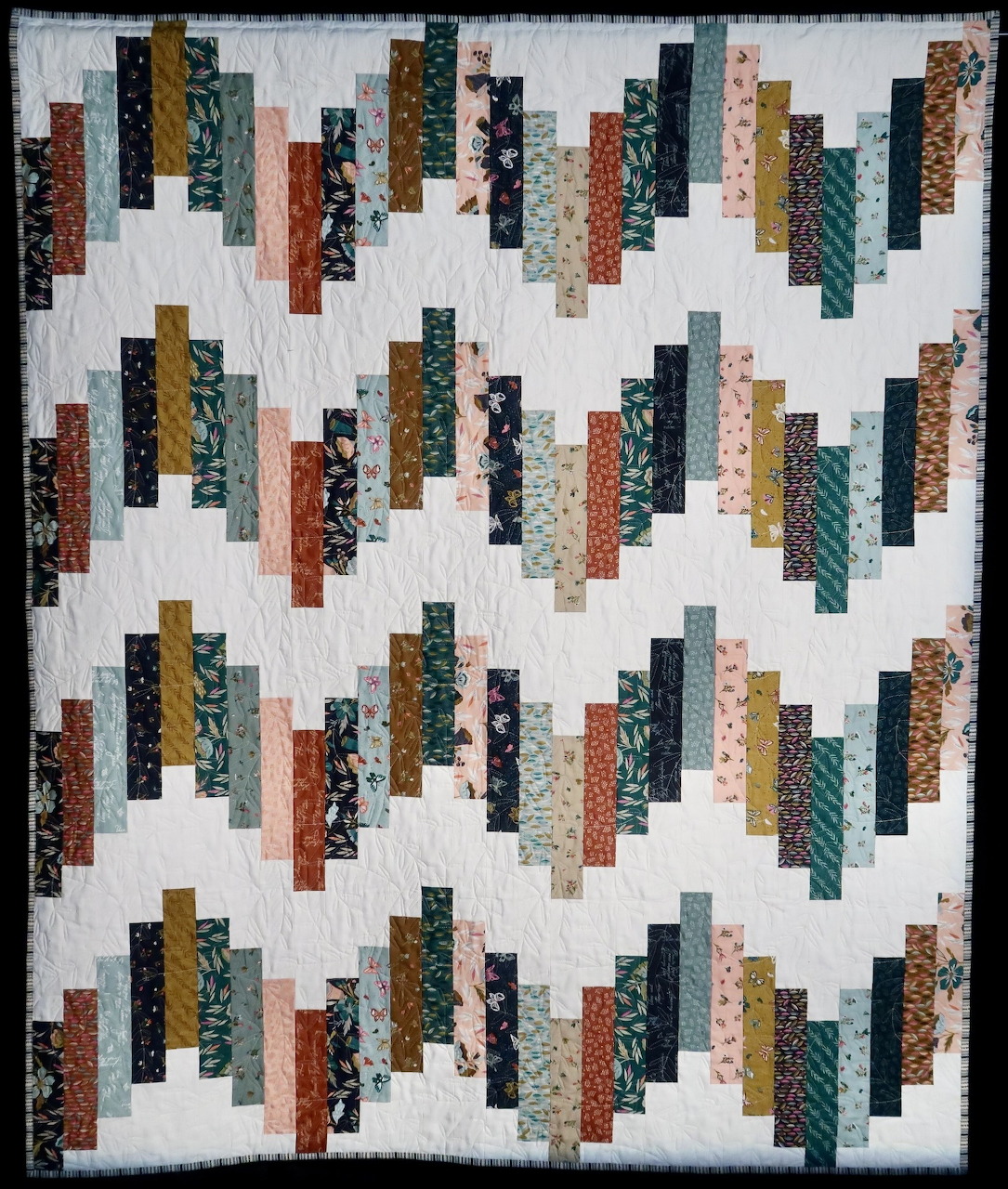 Diagonal strip quilt pattern with colorful fabric strips on white background