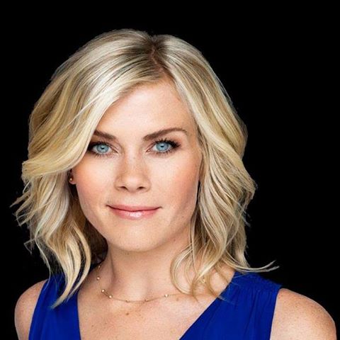 Smiling blonde woman with blue eyes in a blue top on a black background