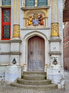 Ornate wooden door in a historic stone facade with gold decoration and curved steps