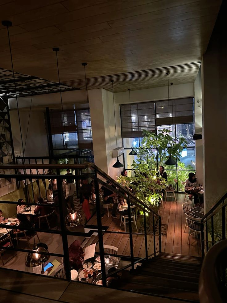 Overhead view of a cozy café with wooden floors, pendant lights, indoor plants, and guests dining