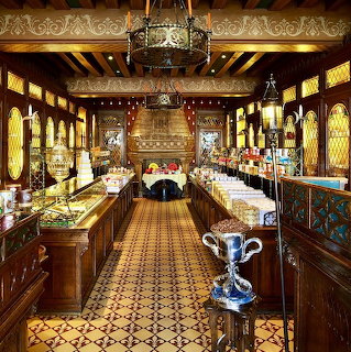 Ornate old confectionery shop interior with wood counters, tiled floor, chandeliers, and stained glass