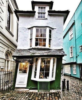 The Crooked House of Windsor, a leaning white and green historic building on a cobblestone street
