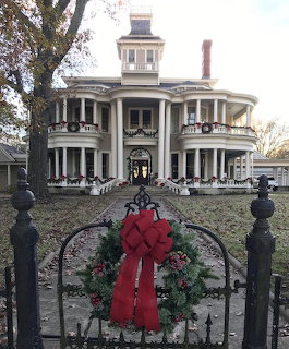 White Victorian mansion with Christmas wreaths and a red bow on iron gate