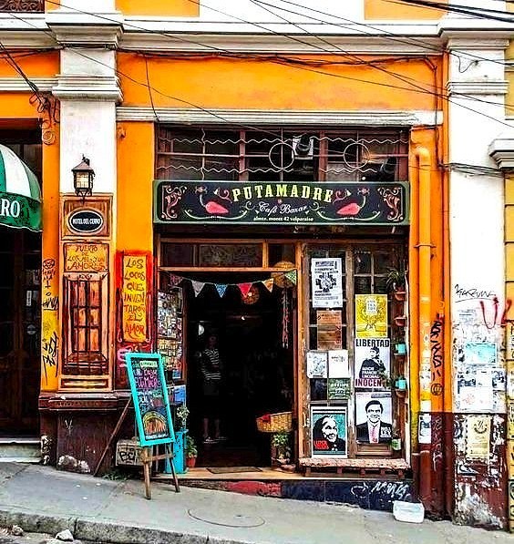 Bright orange cafe storefront with decorative signs and posters in Valparaiso