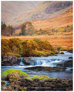 River cascading over rocks in an autumn valley with golden hills and mountains in the background