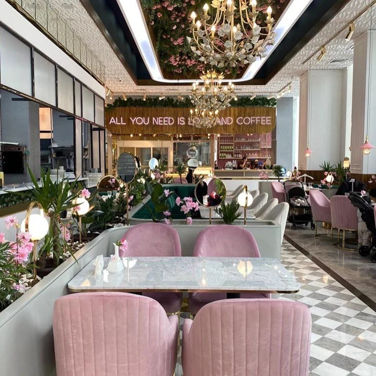 Stylish cafe with pink chairs, marble tables, chandeliers and floral decorations