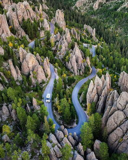 Aerial view of winding road through tall granite rock formations and forest in South Dakota