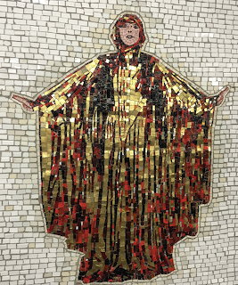 Mosaic of an angelic figure in gold and red robes with arms outstretched against white tile background