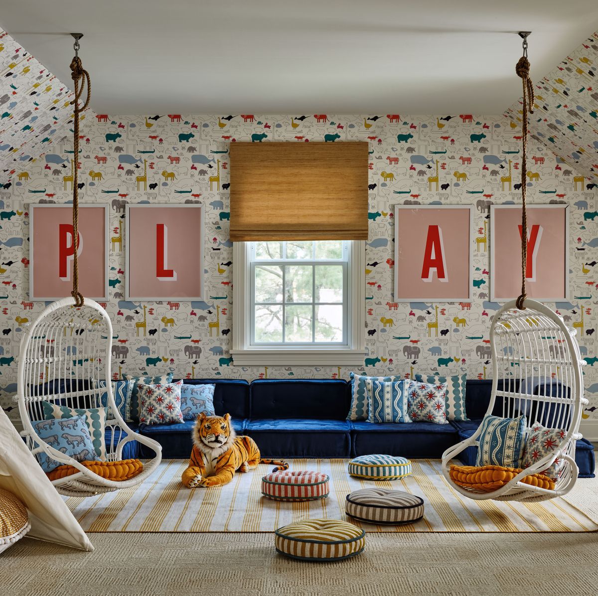 Children's room with blue sofa, hanging wicker chairs, framed letters, and patterned wallpaper