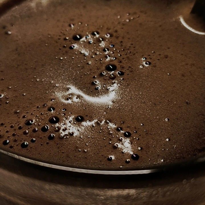 Close-up of dark coffee surface with bubbles and light foam