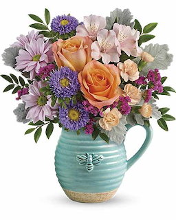 Mixed flower bouquet with roses and daisies in turquoise ceramic vase with bee decoration