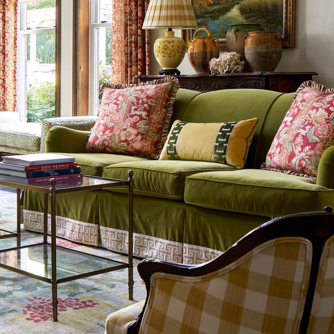 Green sofa with patterned pillows in a classic living room beside a glass coffee table