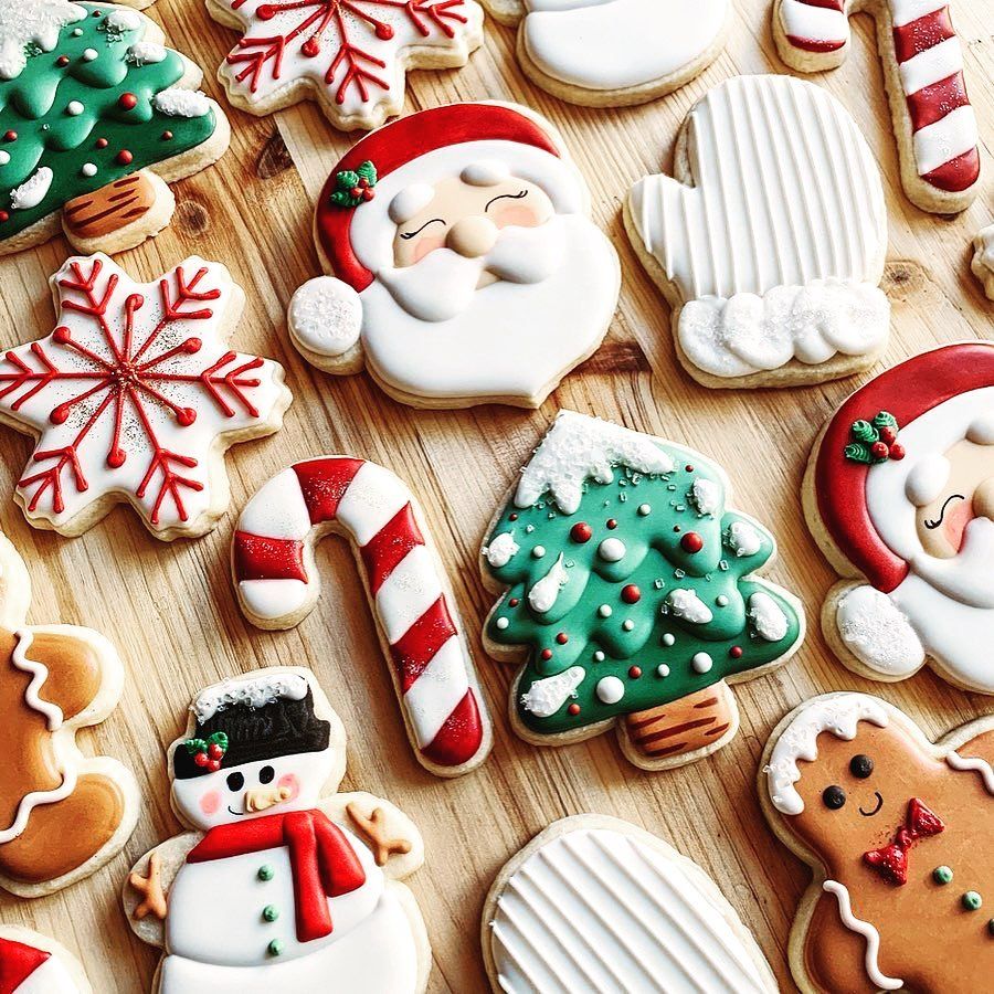 Assortment of decorated Christmas sugar cookies including Santa, snowmen, trees, and candy canes on wood background