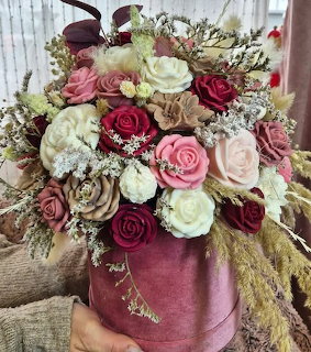 Silk flower bouquet in burgundy pink cream roses with candles in round mauve box held in hands