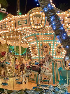 Brightly lit carousel with ornate green and gold trim and horses at night festival