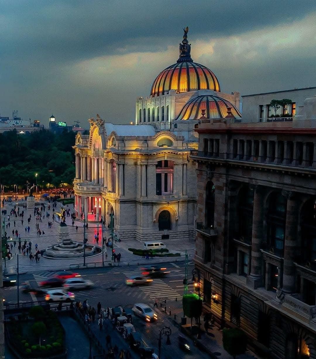 Aerial evening view of Palacio de Bellas Artes, Mexico City, with glowing golden dome and busy streets